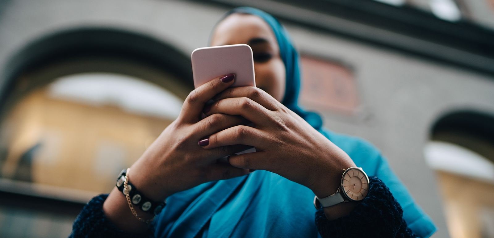 Low angle view of young woman using smart phone against building in city