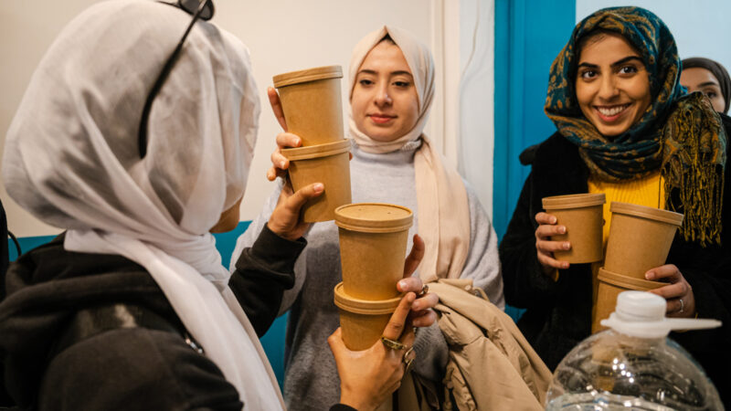 Three hijabi women share a vegetarian meal.