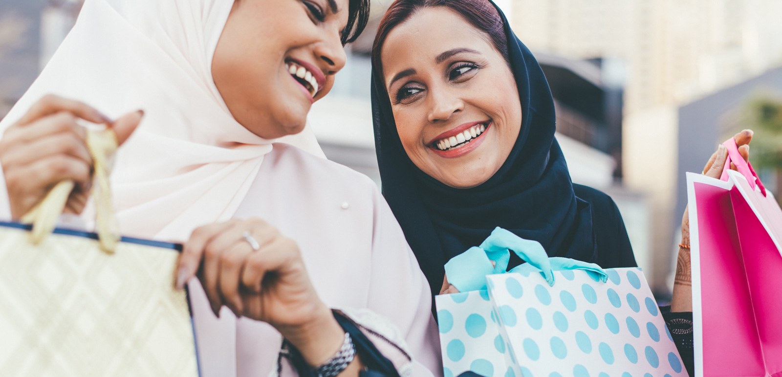 Two smiling Arab women in hijabs with shopping