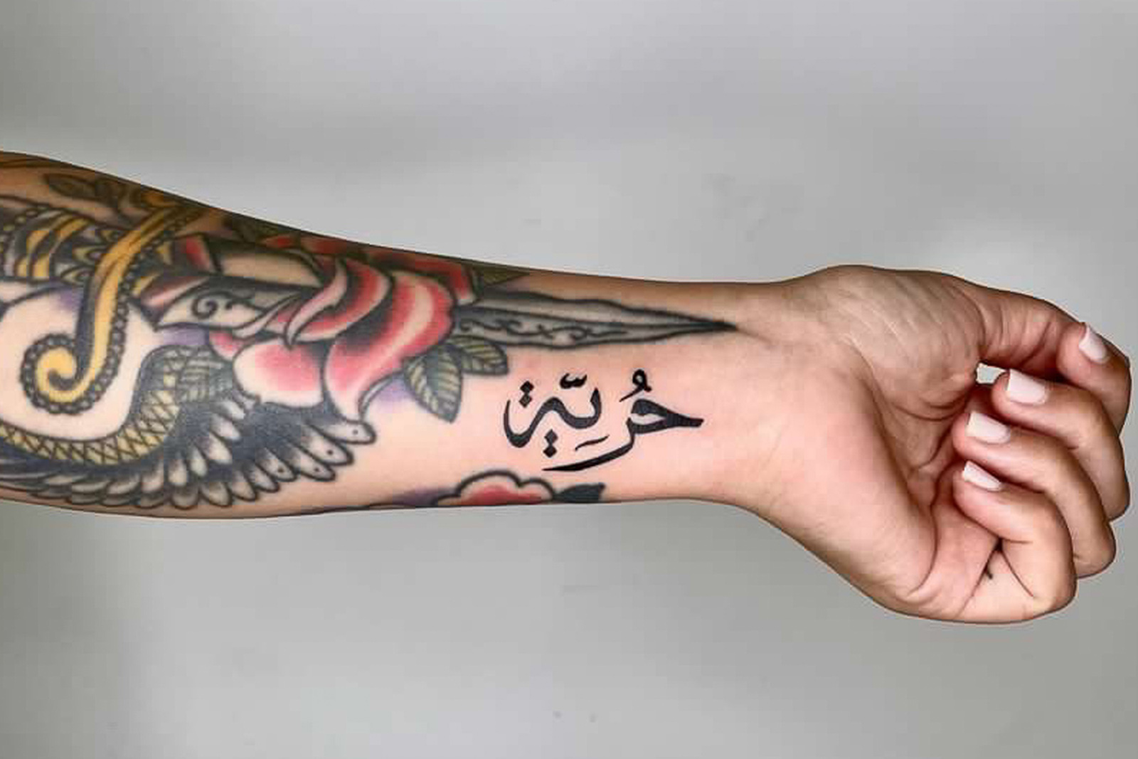 Micro Arabic script tattoo on the inner forearm.