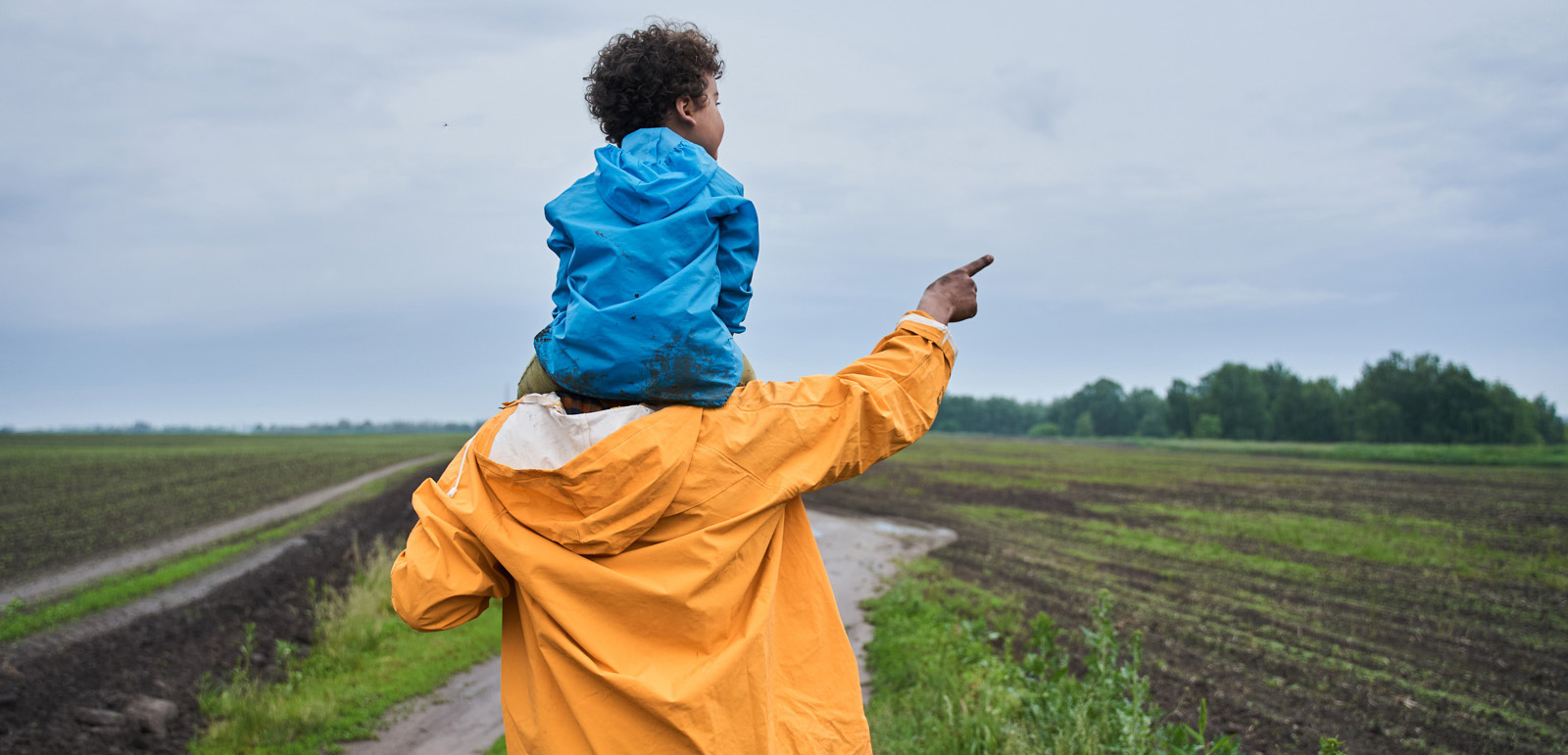 Man holding son on his shoulders while walking along a path