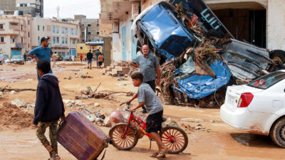 A boy pulls a suitcase past debris in a flash-flood damaged area in Derna, eastern Libya, on September 11, 2023.