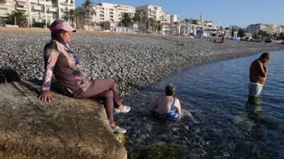 A French woman named Dalila (center) wears a burkini, as she sunbathes, on the beach of Carras, in the city of Nice, southeastern France, on August 26, 2016. - Burkini is a piece of women's clothing for swimming that is in two pieces and that covers the whole body except the face, hands, and feet. (Photo by JEAN-CHRISTOPHE MAGNENET/AFP via Getty Images) Rim-Sarah Alouane on France burkini ban September 2023