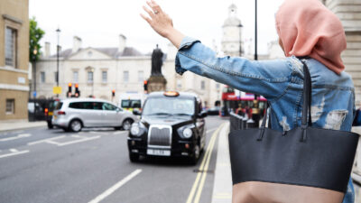 A Muslim woman hails a London black cab.