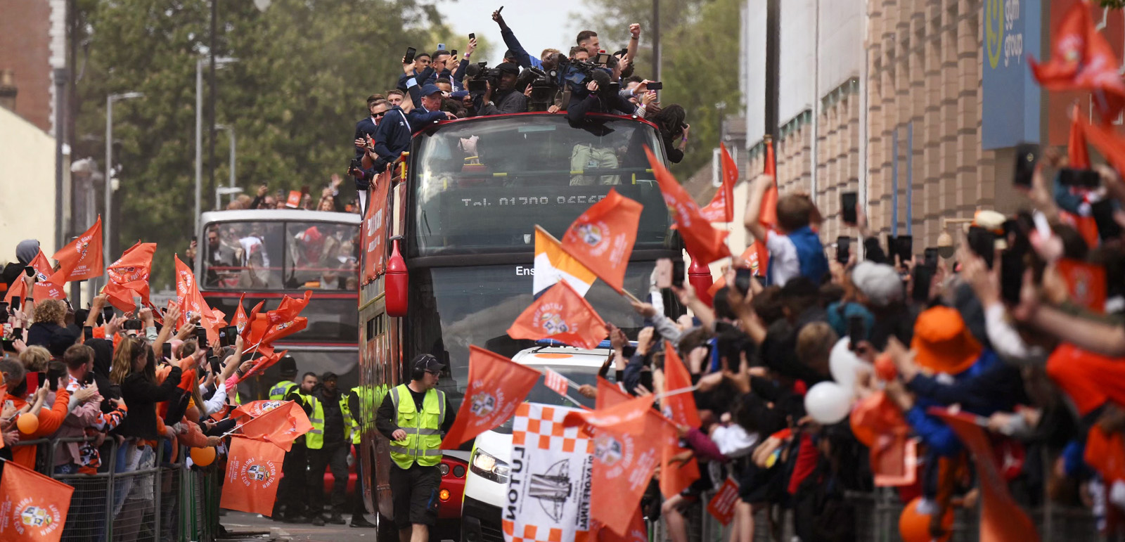 Luton Town football club players and staff parade through the streets of Luton with the Championship playoff trophy in Luton, north of London on May 29, 2023, as they celebrate their promotion to the English Premier League. Luton completed a fairytale journey to the Premier League after winning the Championship playoff final at Wembley on Saturday. Financial experts estimate promotion to world football's most watched league to be worth around £170 million ($210 million) for a club that have been through turmoil since they last played in the top flight 31 years ago. (Photo by Daniel LEAL / AFP) 