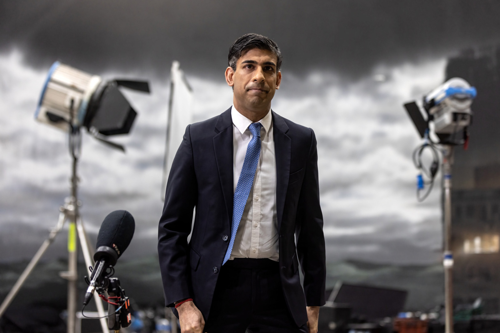 Prime Minister Rishi Sunak in front of a stormy green screen backdrop.