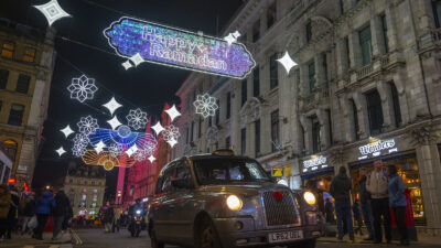 A black cab drives through central London at night.