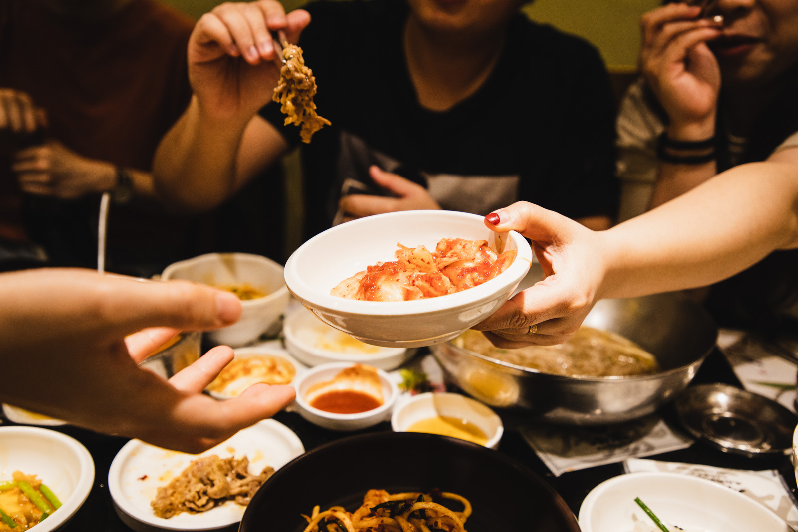Diners pass a bowl of kimchi around the table.