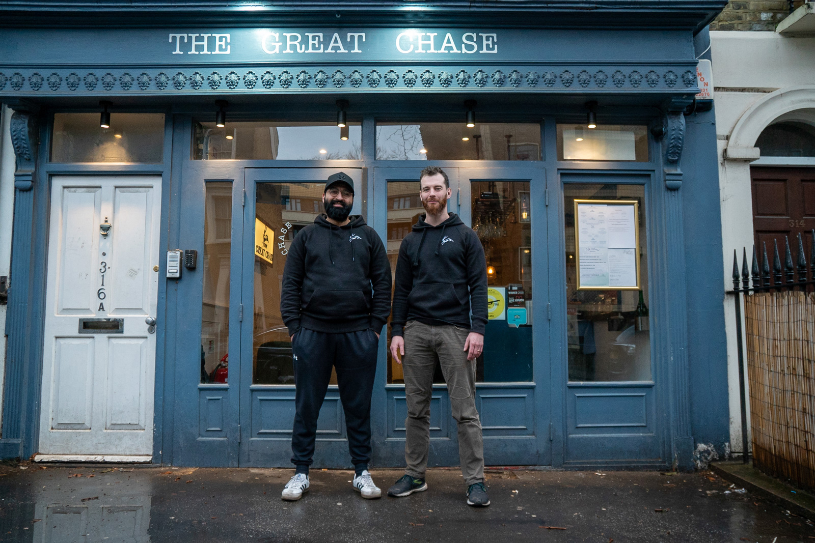 The founders of the Great Chase pose for a photo in front of their restaurant window.
