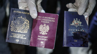 The passports of three deceased foreign aid workers are held up to camera.