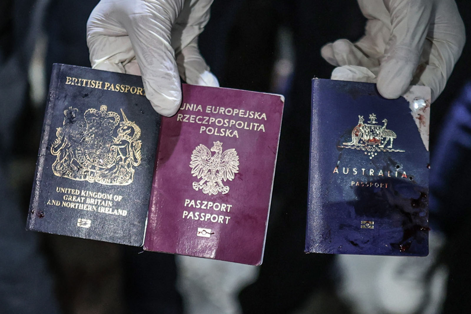 The passports of three deceased foreign aid workers are held up to camera.