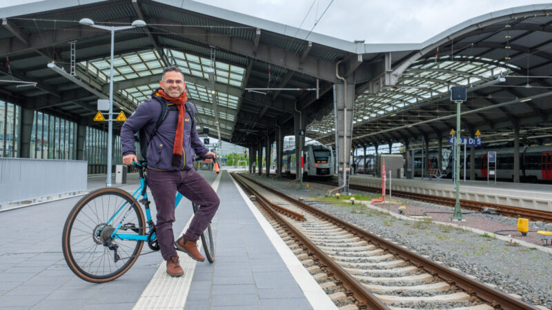 A man on his bike waits for a train on a station platform.