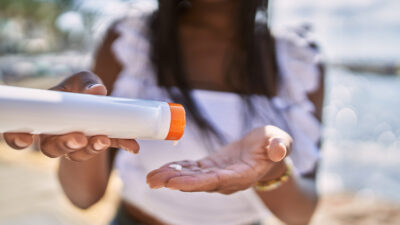 Young african american girl using sunscreen lotion at the beach. Young african american girl using sunscreen lotion at the beach. Stock photo by AaronAmat/Getty Images