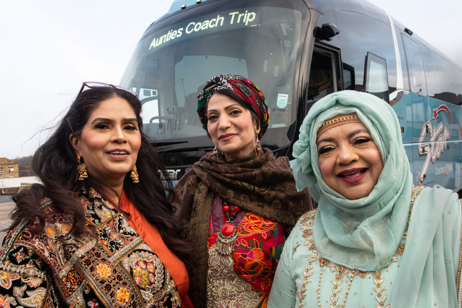 Three women featured in The Bradford Aunties documentary stand in front of a coach. Photo by Tim Smith/BBC Pictures