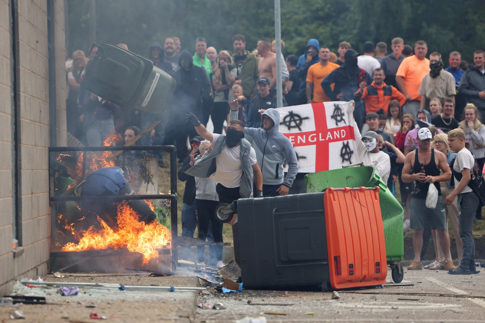 Demonstrators toss a trash bin during an anti-immigration protest, in Rotherham, Britain, August 4, 2024. REUTERS/Hollie Adams