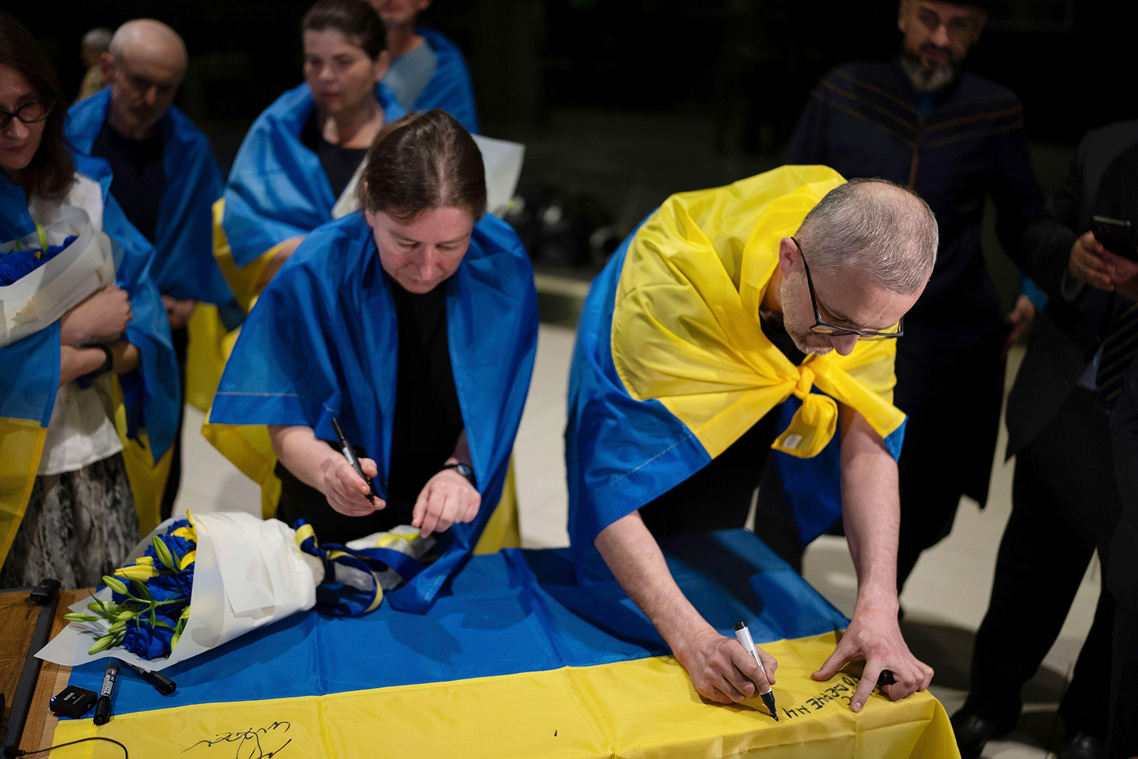 Nariman Dzhelyal, right, deputy head of the Mejlis of the Crimean Tatar People, signs the Ukrainian national flag in Kyiv airport, Ukraine, Saturday, June 29, 2024. Ten Ukrainians who had been held prisoners for years, were released from Russian captivity on Friday with a mediation of Vatican, said Ukraine's President Volodymyr Zelenskyy. Photo by Alex Babenko