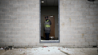 A riot police officer is seen behind a broken window in the Holiday Inn Express being used as an asylum hotel in Manvers, Rotherham on 4 August. Photo by Christopher Furlong/Getty Images