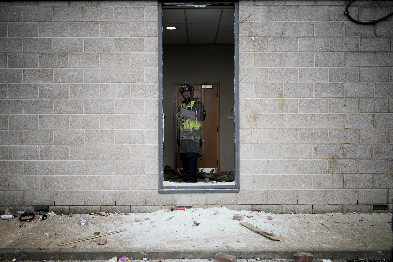 A riot police officer is seen behind a broken window in the Holiday Inn Express being used as an asylum hotel in Manvers, Rotherham on 4 August. Photo by Christopher Furlong/Getty Images