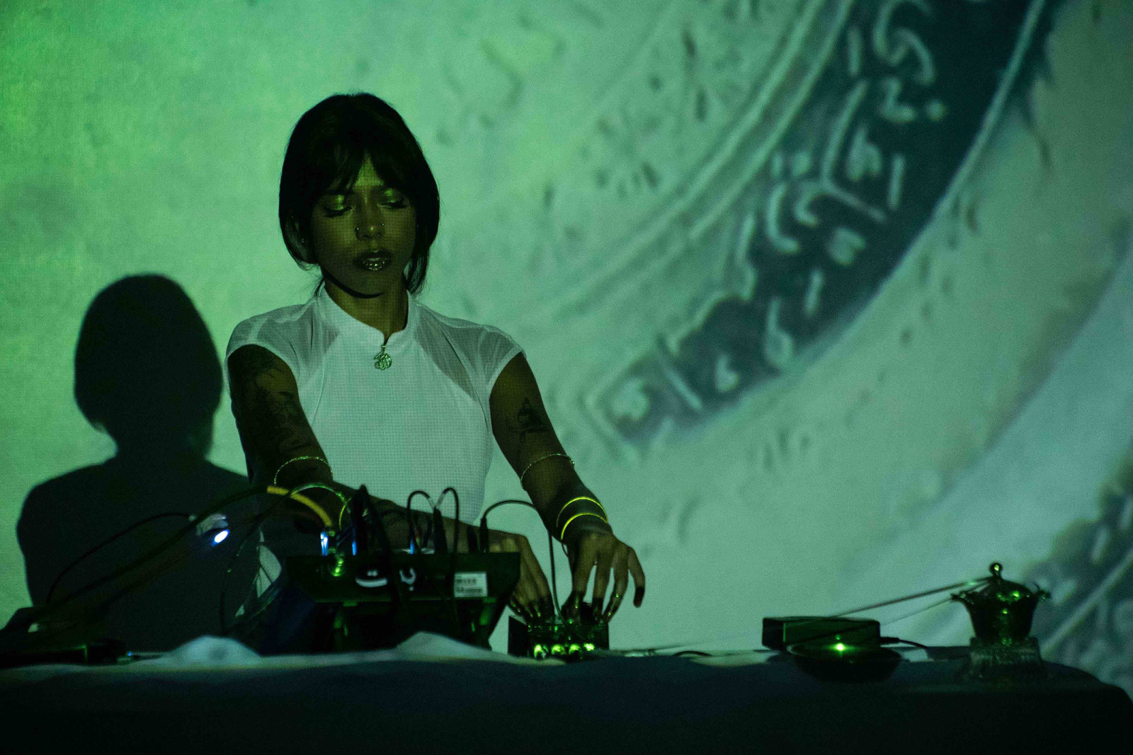 New York-based BINT is pictured behind a DJ deck. BINT uses vocals and drones to create dark ambient soundscapes 