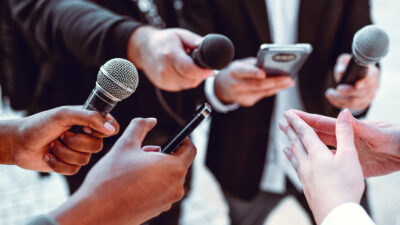 A semicircle of microphones and dictaphones at a press conference