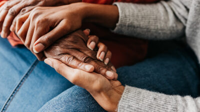 Stock photo close-up of a young daughter holding hands of mother tightly in comfort and reassurance.