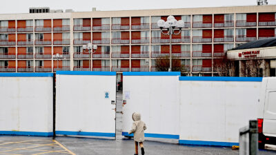 A child runs outside the gates of the Crowne Plaza hotel, which is housing asylum seekers as they wait for their asylum claims to be processed, at Heathrow in west London, on February 16, 2021.