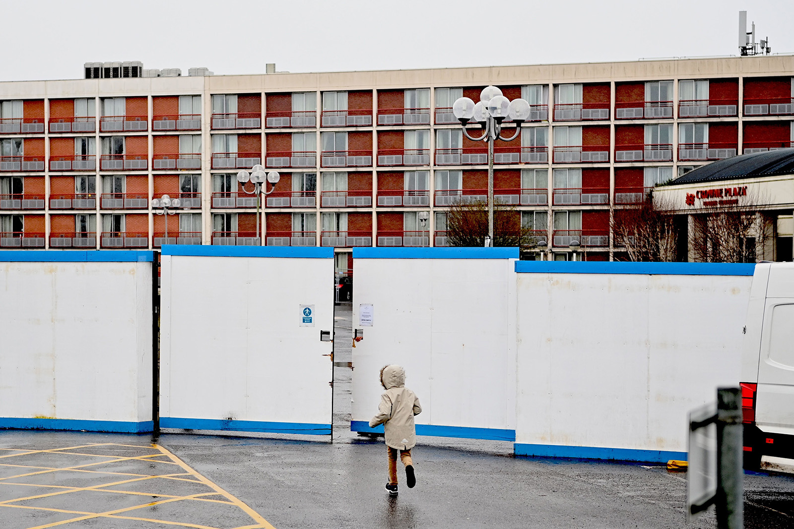 A child runs outside the gates of the Crowne Plaza hotel, which is housing asylum seekers as they wait for their asylum claims to be processed, at Heathrow in west London, on February 16, 2021.