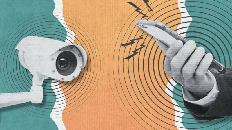 A CCTV camera and a hand holding a mobile phone