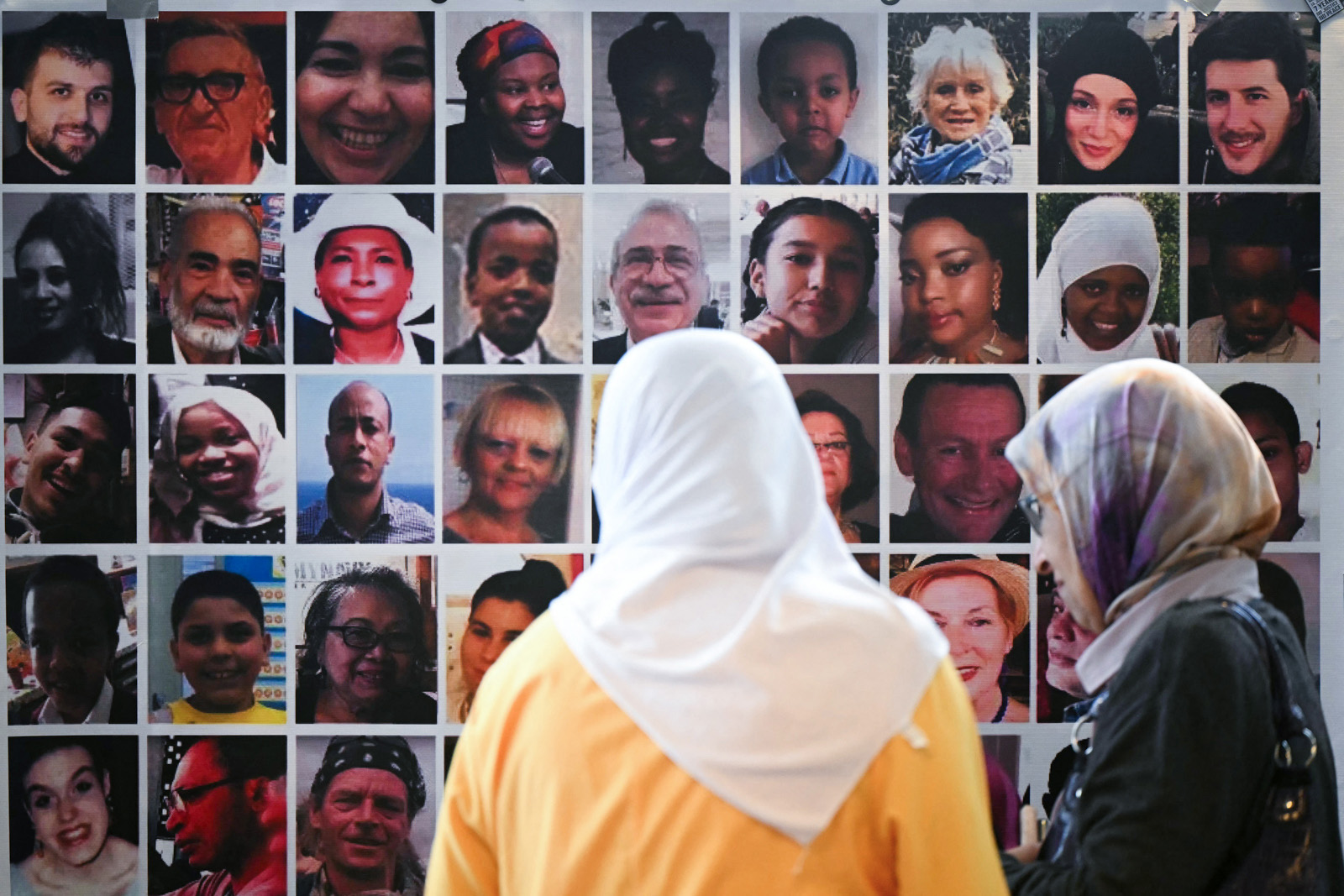 Menana Jabari a relative of the victims of the Grenfell Tower fire disaster looks at a wall displaying pictures of the 72 people killed by the blaze, as she arrives to attend a press conference at the Royal Lancaster Hotel, in London, on 4 September following the publication of the Grenfell Tower Inquiry. 