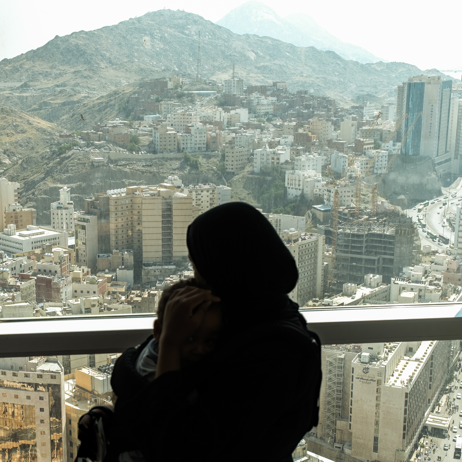 Woman and child looking out of a window over the mountains in Mecca.