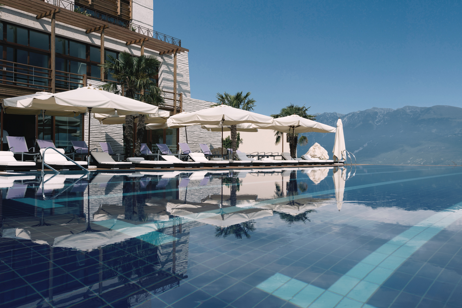 View of the pool with white umbrellas in the background at Lefay Resort and Spa, Lake Garda, Italy