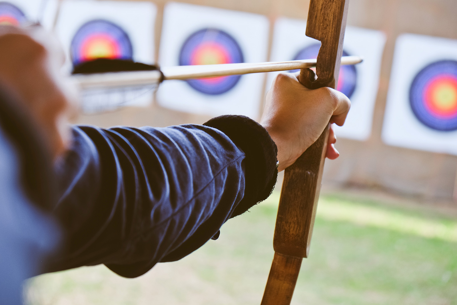 close up image of Archer holds his bow aiming at a target. 