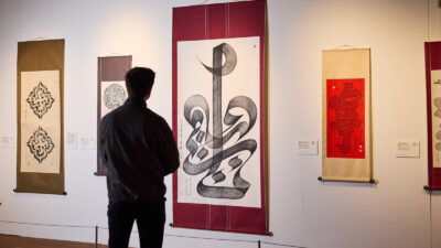 A man looks at a large wall hanging of calligraphy