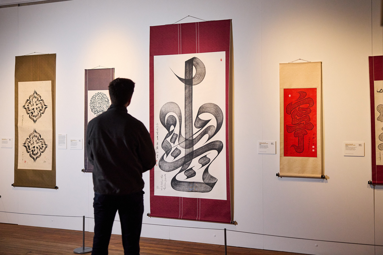 A man looks at a large wall hanging of calligraphy