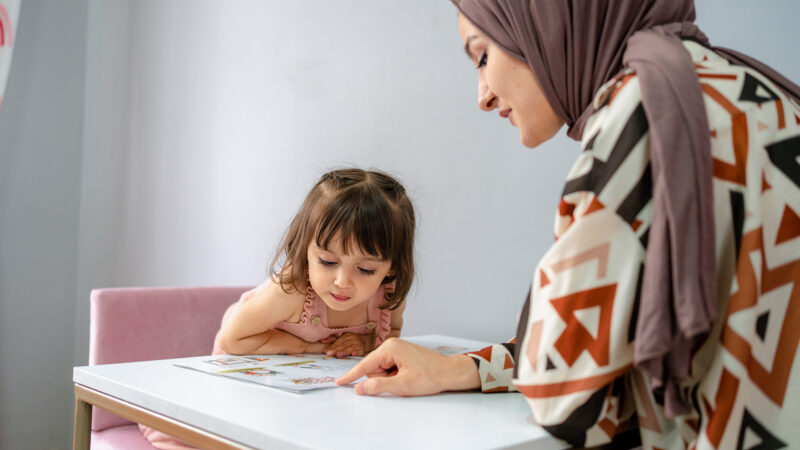 Training and education of children, a girl with her mother and a book at home read a textbook.