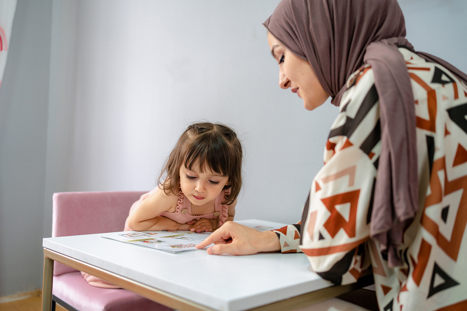 Training and education of children, a girl with her mother and a book at home read a textbook. 