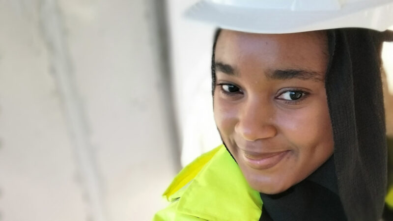 A Muslim construction worker wearing a hijab under her hard hat