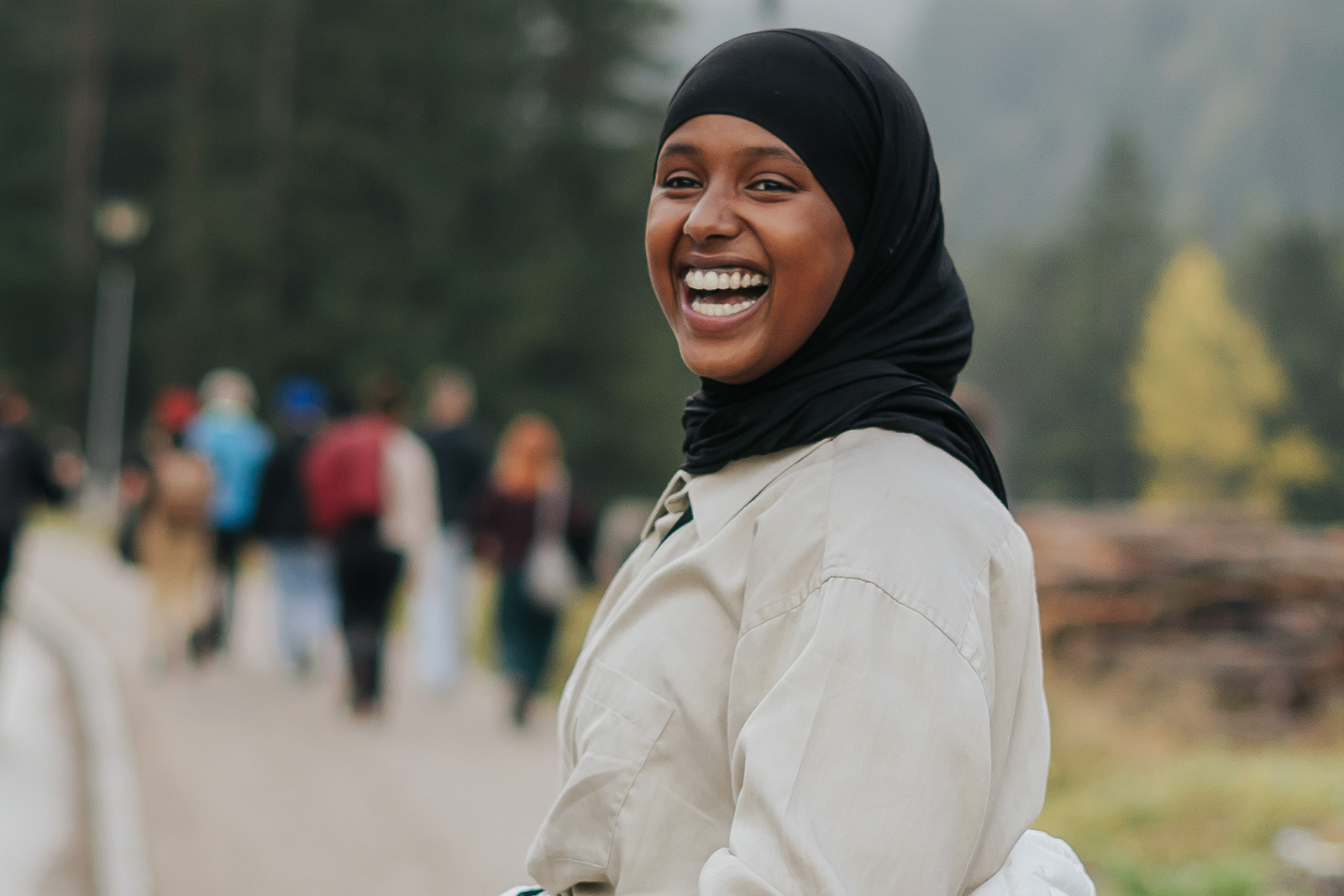 Amina Hassan on a walking path, wearing a black hijab, laughing