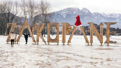 Tourists take pictures at a vantage point with a wooden Zakopane sign on the Górna Równia Krupowa in Zakopane, Poland, January 9, 2025.