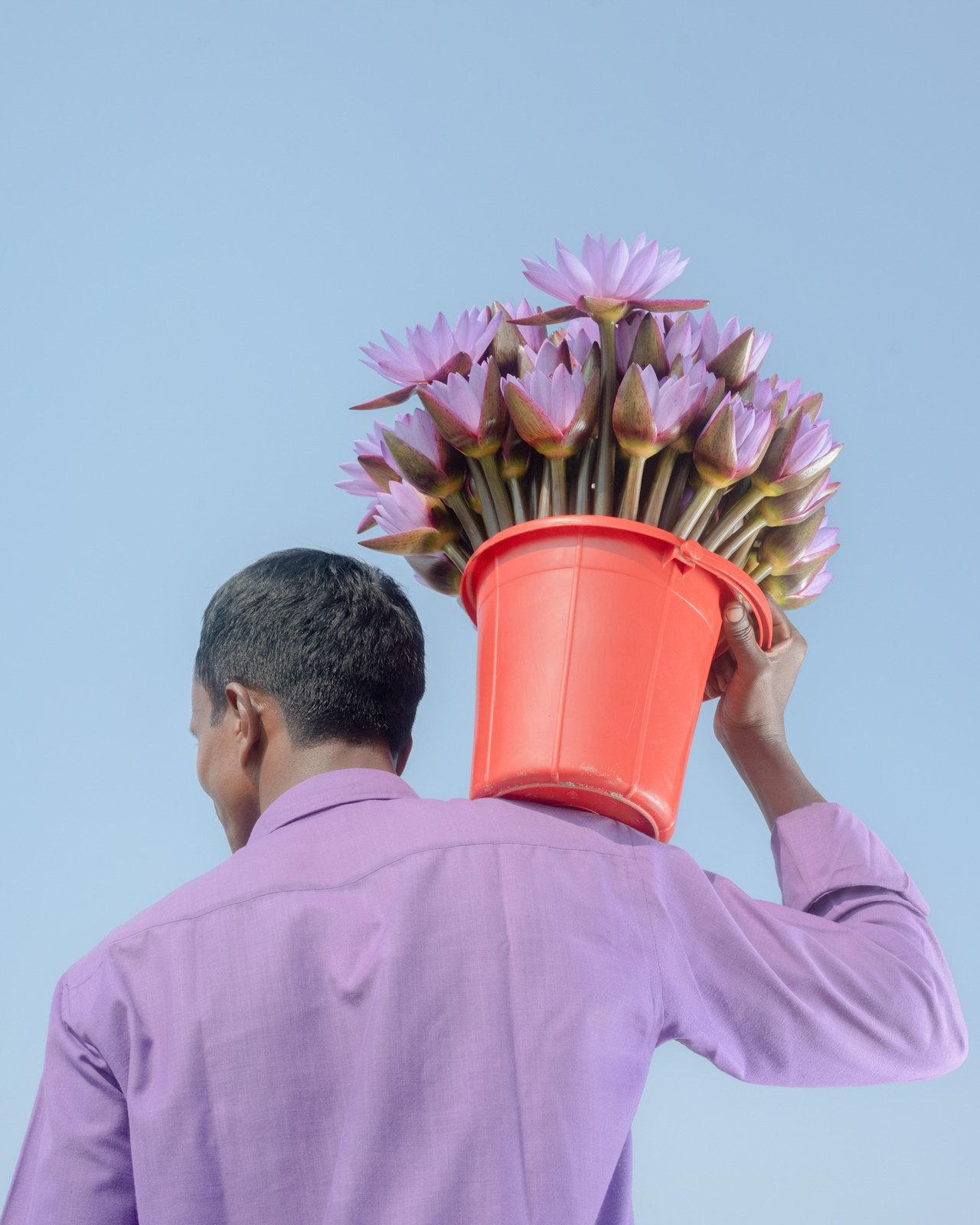 Man holding bucket of flowers on his shoulder