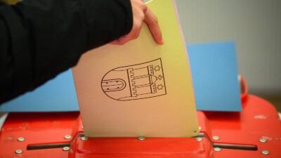 A voter casts a ballot paper with the coat of arms of the city of Hamburg into an urn at a polling station for the state parliament elections in Hamburg on March 2, 2025.