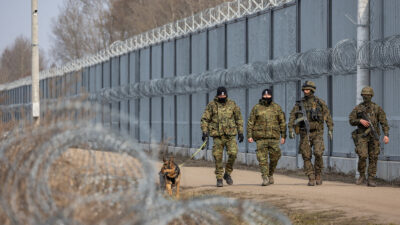 Polish border guard officers and soldiers patrol beside a fence built to curb irregular immigration at the Belarusian border in Ozierany Male, eastern Poland, on March 22, 2025.