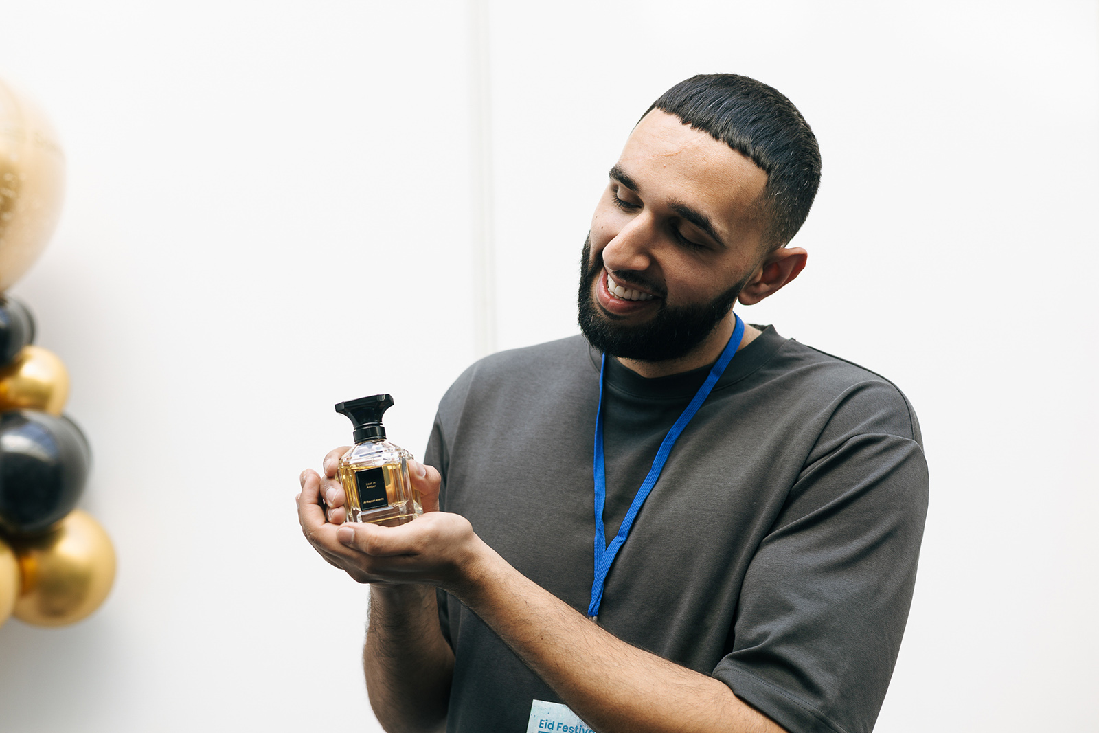 Founder Rain Mahmood wearing a grey t-shirt and holding a bottle of perfume