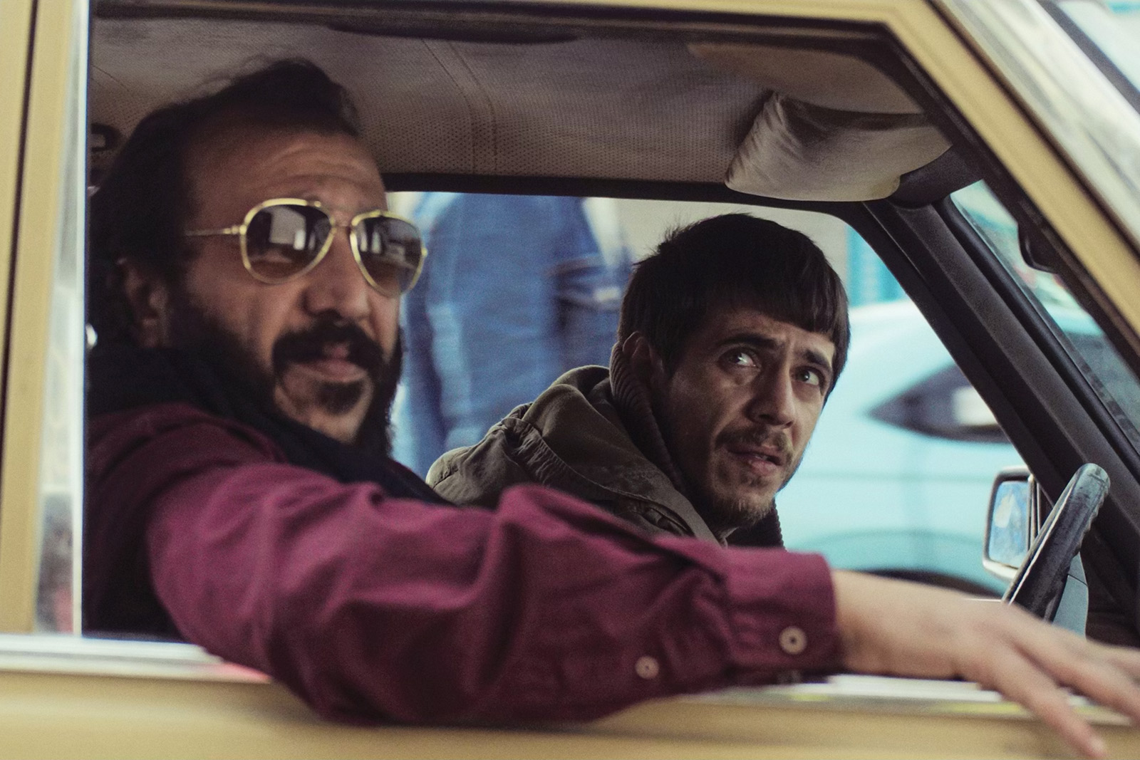 Two men in the front of a yellow car