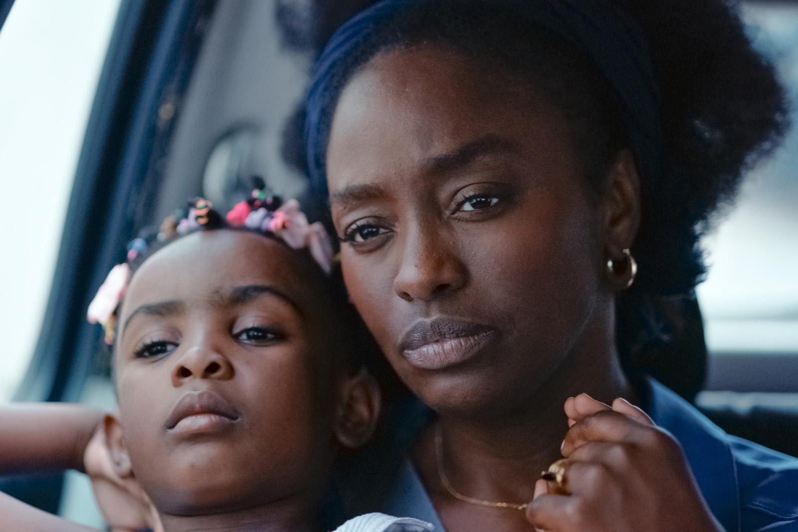 A mother travelling in a car with her daughter on her lap