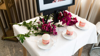 Flowers and candles are on a table in memory of a woman who died a week ago and whose family is about say goodbye to her body.