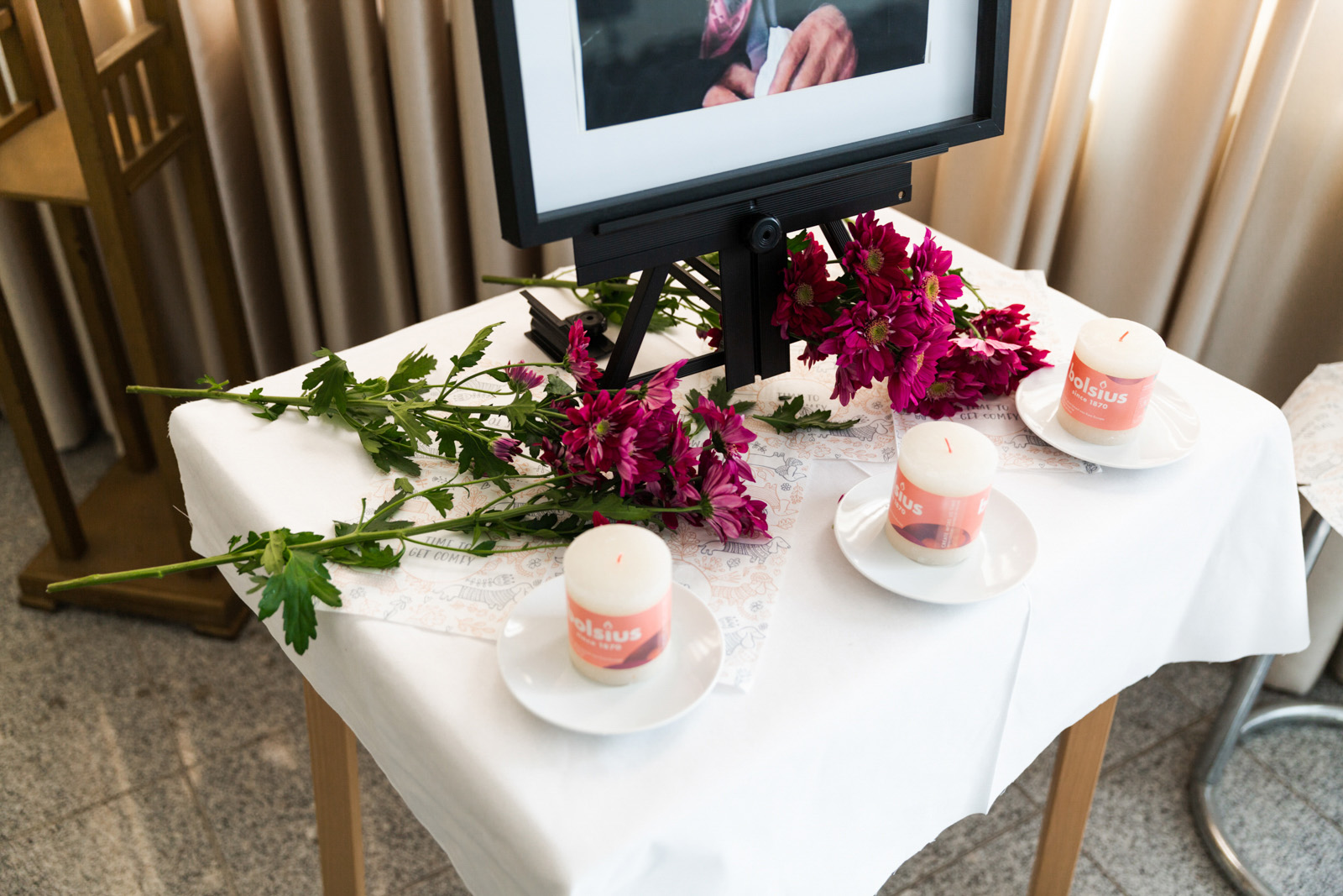 Flowers and candles are on a table in memory of a woman who died a week ago and whose family is about say goodbye to her body.