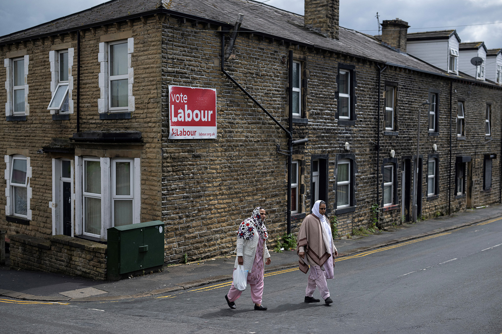 Two women walk past a sign encouraging people to vote for the Labour Party in the forthcoming general election in the town centre of Keighley, northwest England, on June 14, 2024. Gaza is a long way from the picturesque foothills of the Yorkshire Dales but the issue could swing UK general election races in northern England, with many local Muslims angry at Labour's stance. While Labour is expected to win a thumping national majority on July 4, leader Keir Starmer's refusal to back an unconditional ceasefire in Gaza has caused a split with once-loyal Muslim supporters.