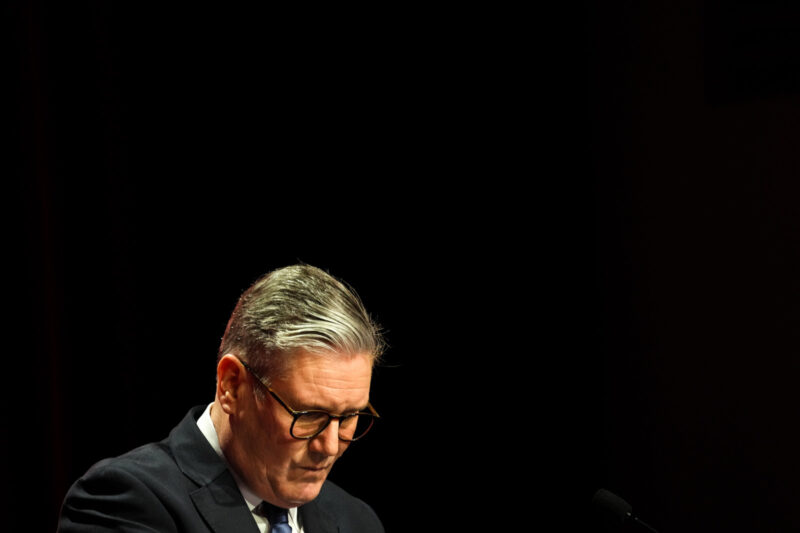 Keir Starmer looks down against black background