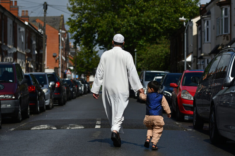 A man and child walk along a residential street in the Lozells area of Birmingham, central England on 22 August, 2020.
